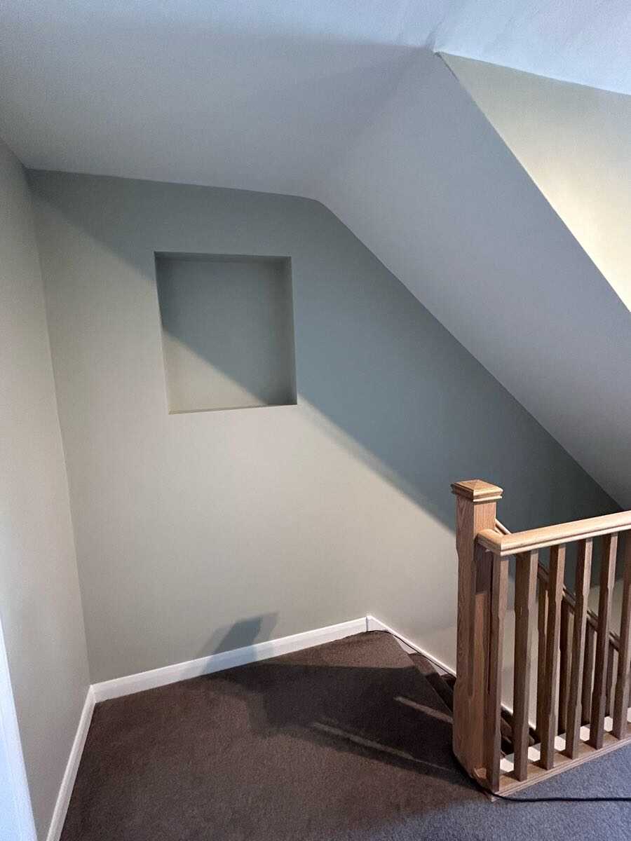 Freshly painted staircase landing with sage grey walls and white skirting boards
